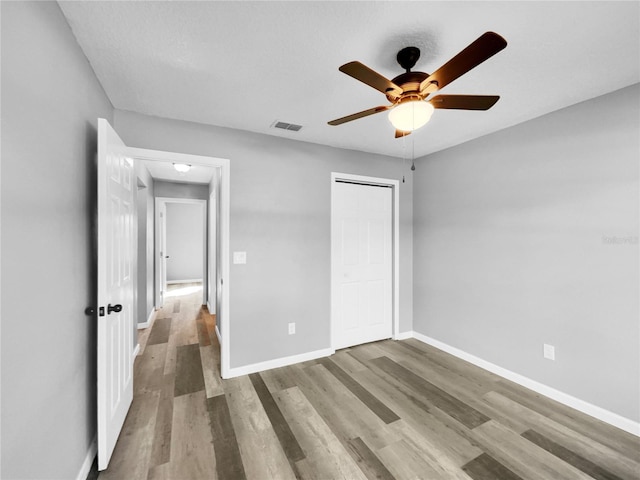 unfurnished bedroom featuring wood-type flooring, a closet, and ceiling fan