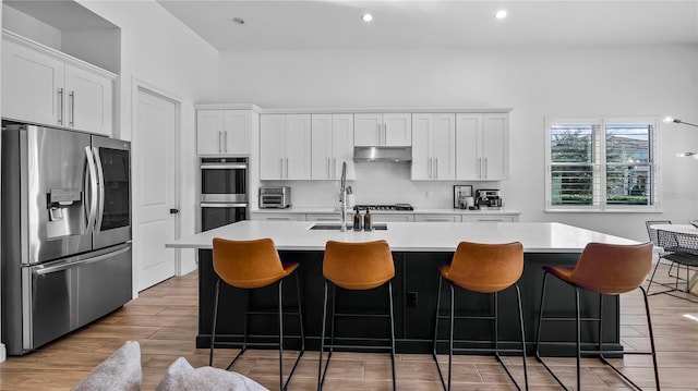 kitchen featuring sink, stainless steel appliances, an island with sink, and white cabinets