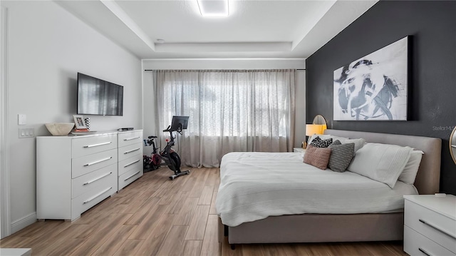 bedroom with a tray ceiling and light hardwood / wood-style flooring