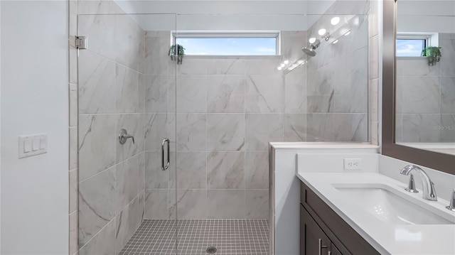 bathroom featuring vanity, a shower with shower door, and a healthy amount of sunlight