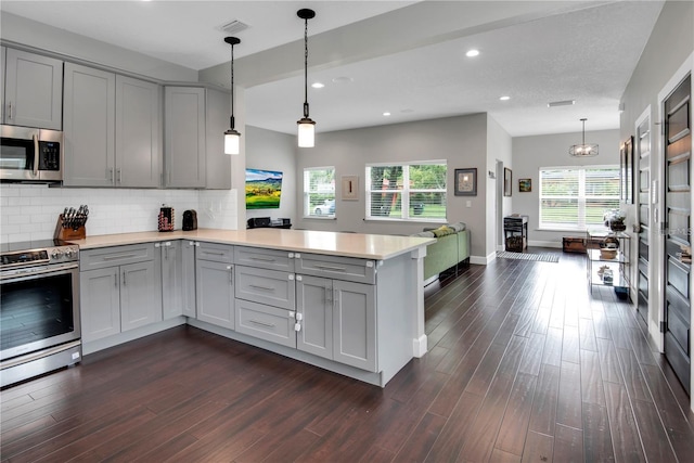 kitchen featuring appliances with stainless steel finishes, gray cabinets, kitchen peninsula, and decorative backsplash