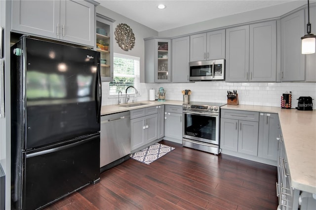 kitchen with dark wood-type flooring, sink, decorative light fixtures, appliances with stainless steel finishes, and backsplash