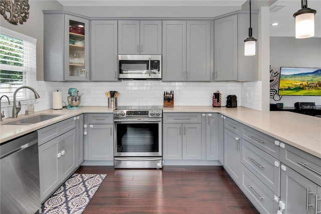 kitchen with stainless steel appliances, sink, decorative backsplash, and decorative light fixtures