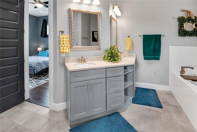 bathroom with vanity, a relaxing tiled tub, tile patterned floors, and ceiling fan