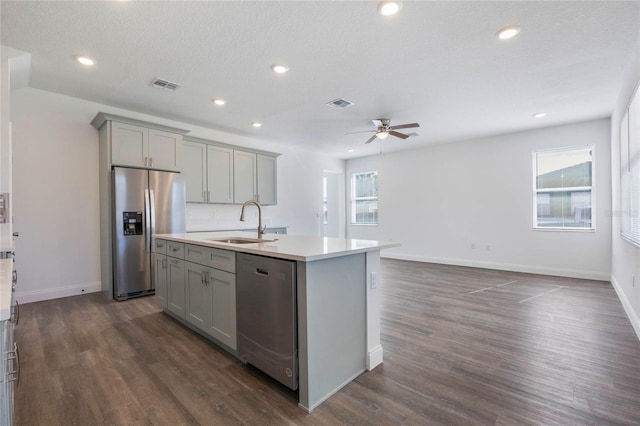 kitchen with sink, gray cabinets, an island with sink, and appliances with stainless steel finishes