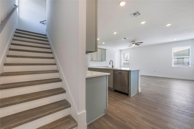 stairs featuring wood-type flooring, sink, and ceiling fan