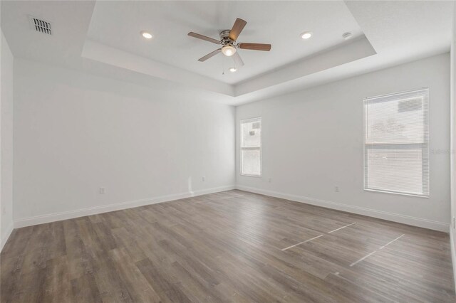 unfurnished room with a healthy amount of sunlight, hardwood / wood-style floors, and a tray ceiling