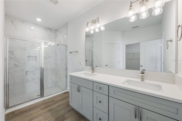 bathroom with wood-type flooring, a shower with door, and vanity