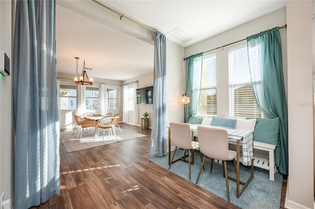 dining room featuring dark wood-type flooring, plenty of natural light, and an inviting chandelier