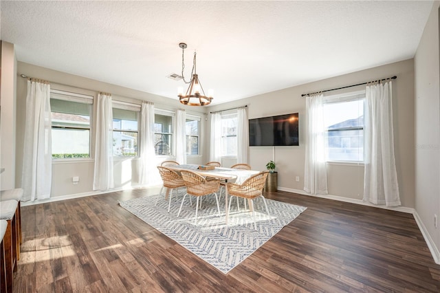 dining room with plenty of natural light, dark wood-type flooring, and a chandelier