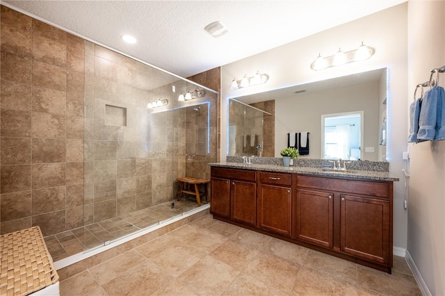 bathroom featuring visible vents, double vanity, walk in shower, a sink, and a textured ceiling