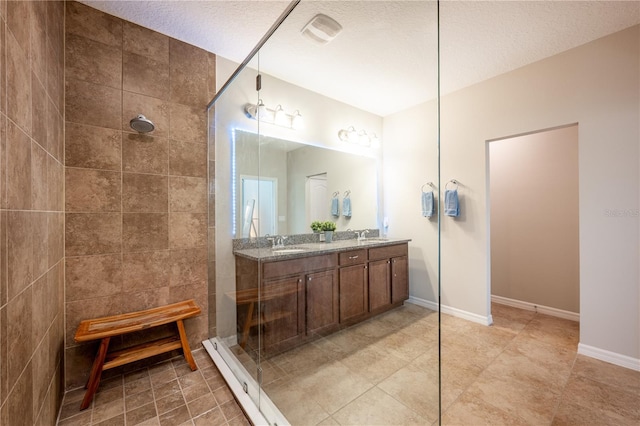 bathroom with vanity, a tile shower, and a textured ceiling