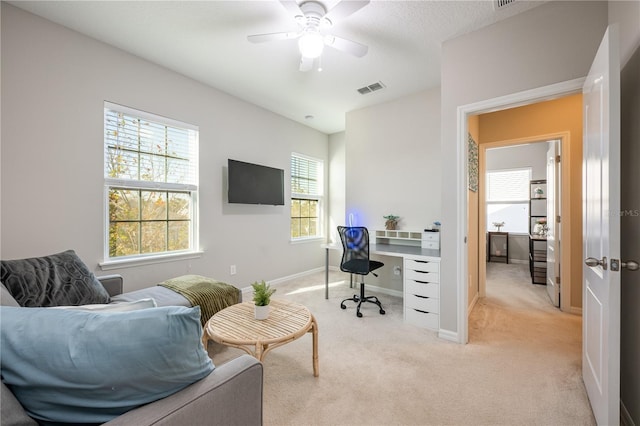 home office featuring baseboards, light carpet, visible vents, and ceiling fan