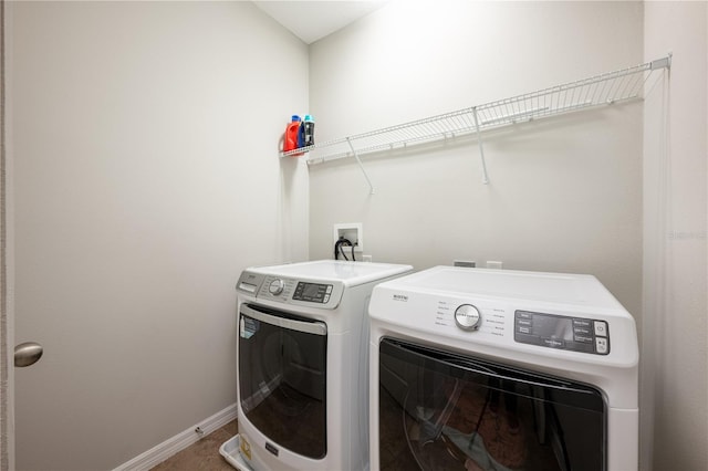 clothes washing area featuring laundry area, baseboards, and washing machine and clothes dryer