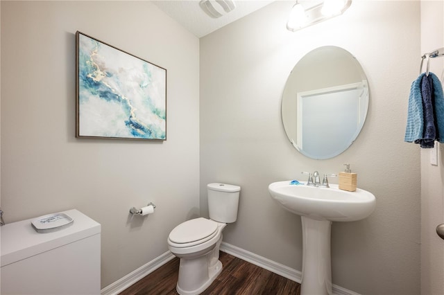 bathroom featuring visible vents, toilet, a sink, wood finished floors, and baseboards