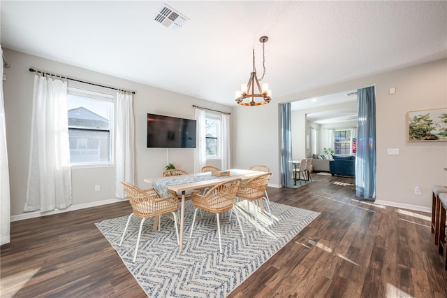 dining space featuring baseboards, visible vents, dark wood-style flooring, and a chandelier