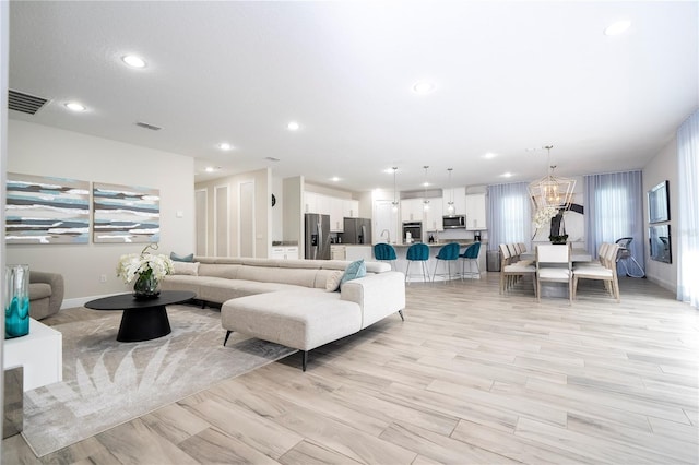 living room featuring a healthy amount of sunlight, light hardwood / wood-style flooring, and a chandelier