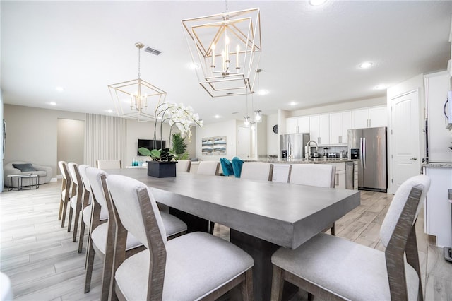 dining area with a notable chandelier, light hardwood / wood-style floors, and sink