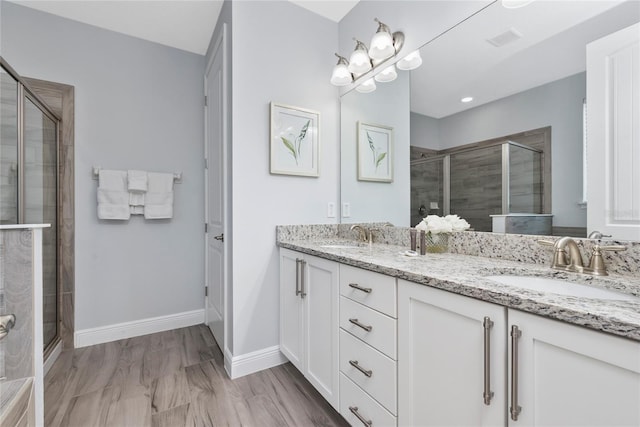 bathroom featuring a shower with door and vanity