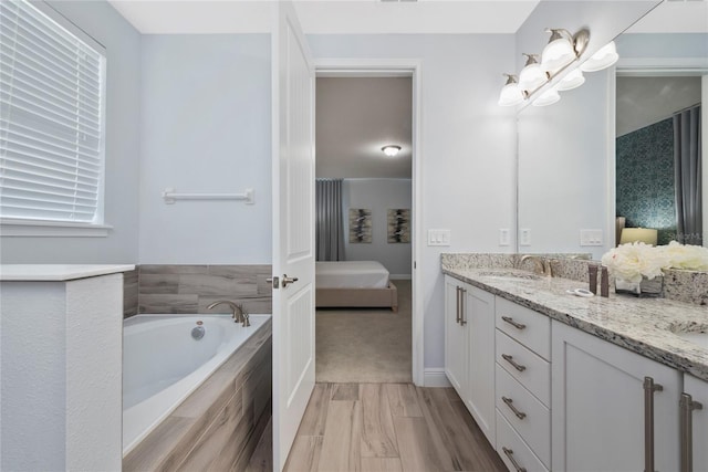 bathroom featuring vanity and tiled bath