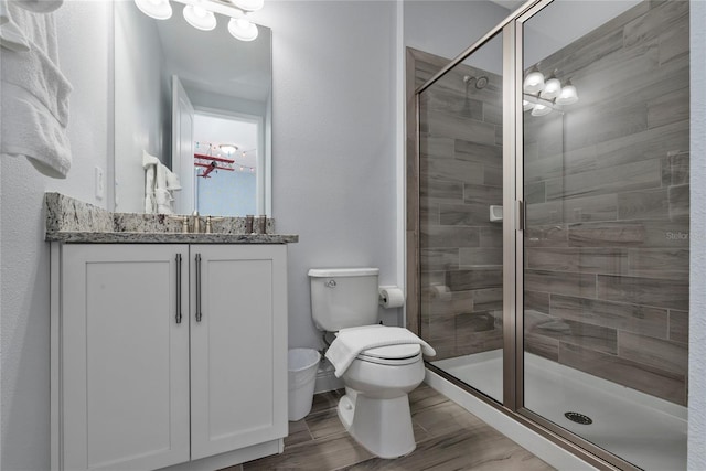 bathroom featuring vanity, hardwood / wood-style flooring, a shower with door, and toilet