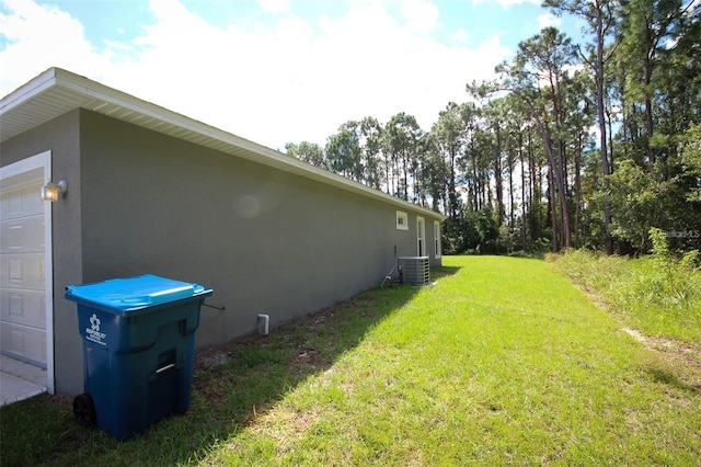 view of yard featuring a garage and central AC