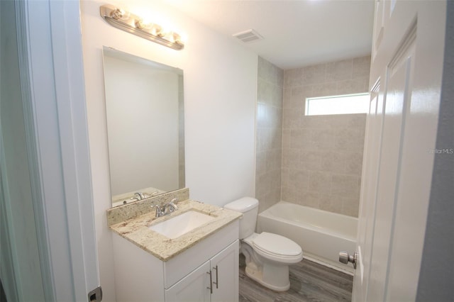 full bathroom with tiled shower / bath, vanity, toilet, and hardwood / wood-style floors