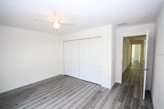 unfurnished bedroom featuring hardwood / wood-style floors, a closet, and ceiling fan