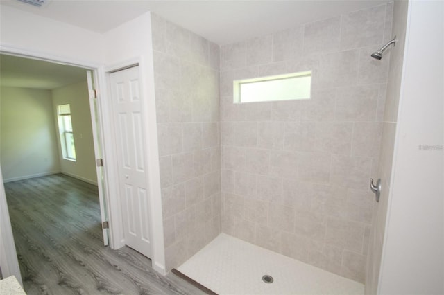 bathroom with tiled shower and wood-type flooring