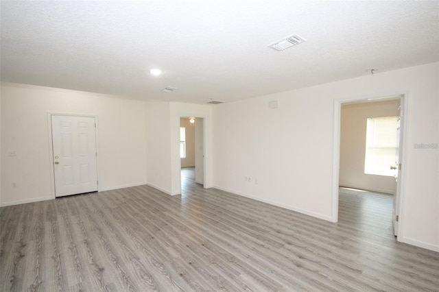 unfurnished room featuring a textured ceiling and light wood-type flooring