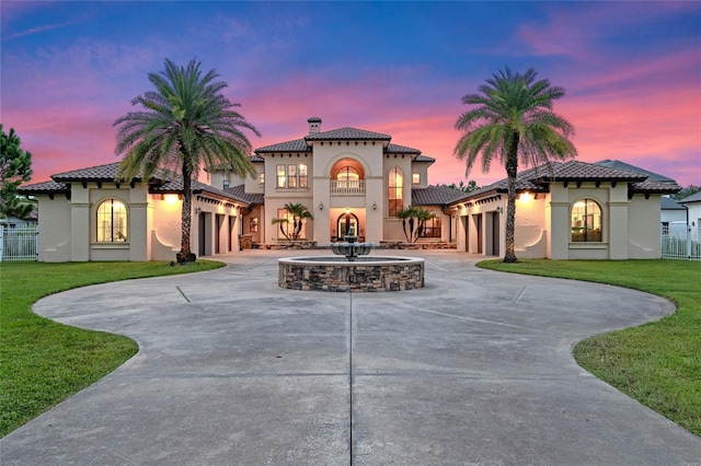 mediterranean / spanish-style house featuring a garage, a balcony, and a lawn