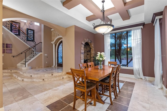 tiled dining space with beamed ceiling, coffered ceiling, and a towering ceiling