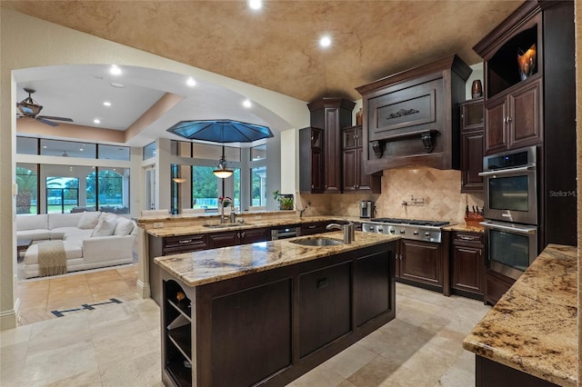 kitchen featuring sink, a center island with sink, light stone countertops, and appliances with stainless steel finishes