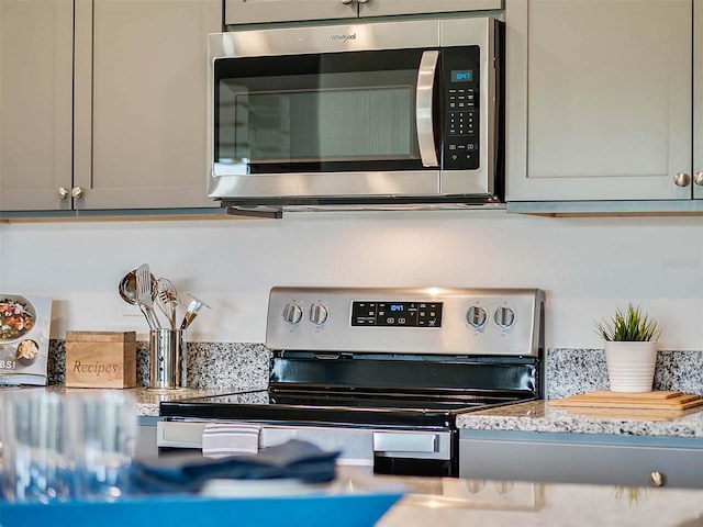 details with electric stove, gray cabinets, and light stone counters