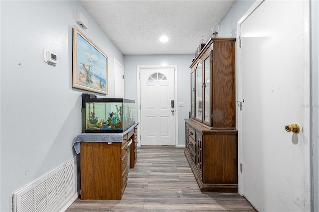 entryway with wood-type flooring and a textured ceiling