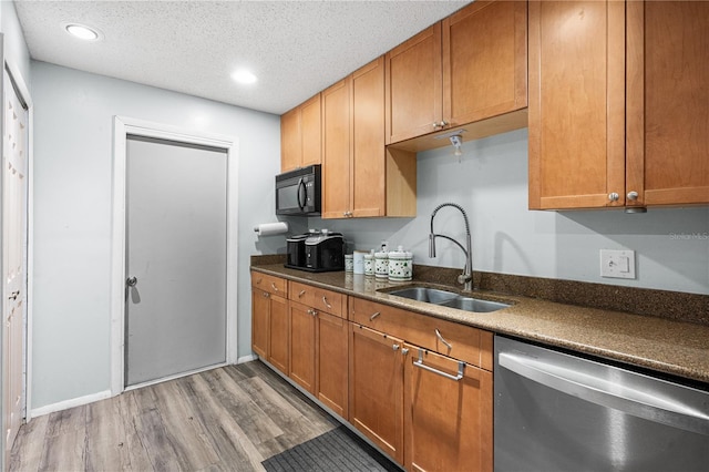 kitchen featuring dark wood-type flooring, stainless steel dishwasher, sink, and a textured ceiling