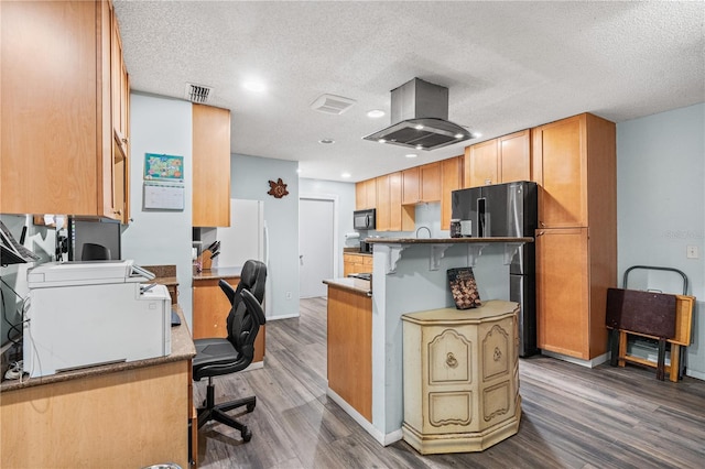 kitchen with island range hood, stainless steel fridge, a kitchen breakfast bar, and dark hardwood / wood-style floors