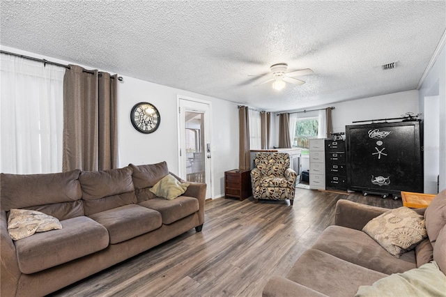 living room featuring ceiling fan, dark wood-type flooring, and a textured ceiling