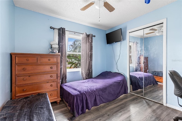 bedroom featuring dark wood-type flooring, a textured ceiling, ceiling fan, and a closet