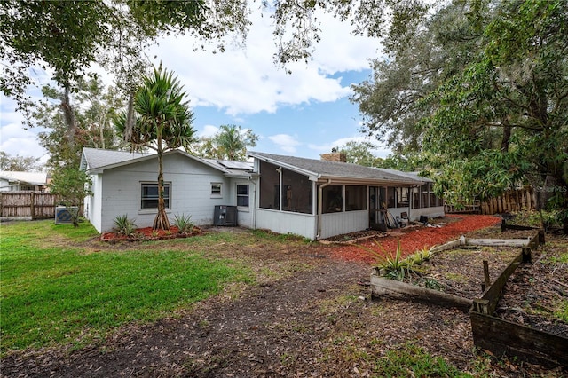 rear view of house with a sunroom, central AC unit, and a lawn