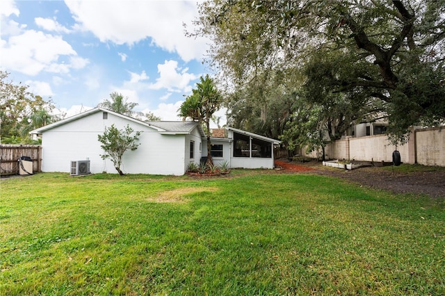 back of house with central AC unit, a lawn, and a sunroom