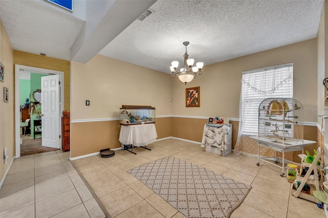 tiled dining area featuring an inviting chandelier, baseboards, visible vents, and a textured ceiling