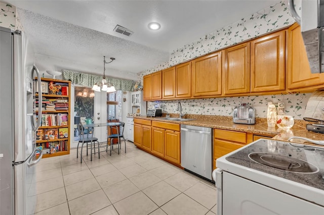 kitchen featuring a textured ceiling, stainless steel appliances, a sink, visible vents, and an inviting chandelier