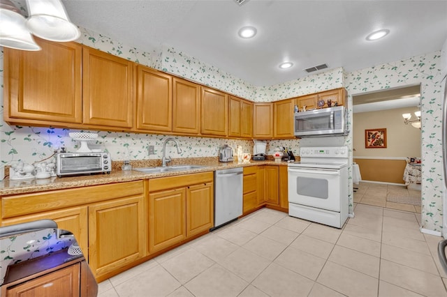 kitchen featuring light tile patterned flooring, a toaster, stainless steel appliances, a sink, and visible vents