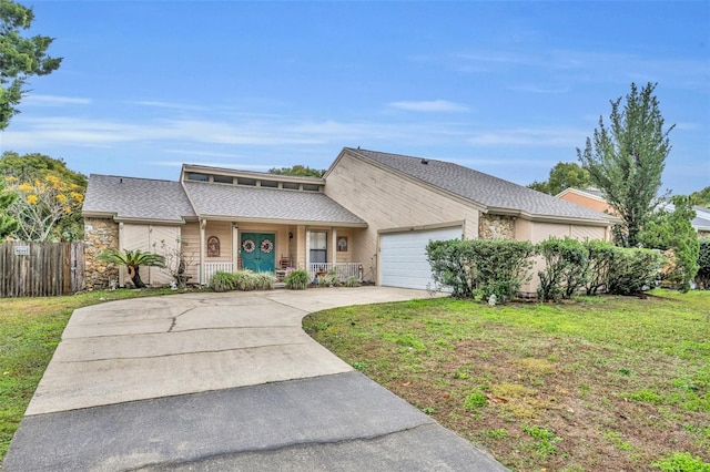 view of front of home featuring a garage, fence, driveway, stone siding, and a front yard