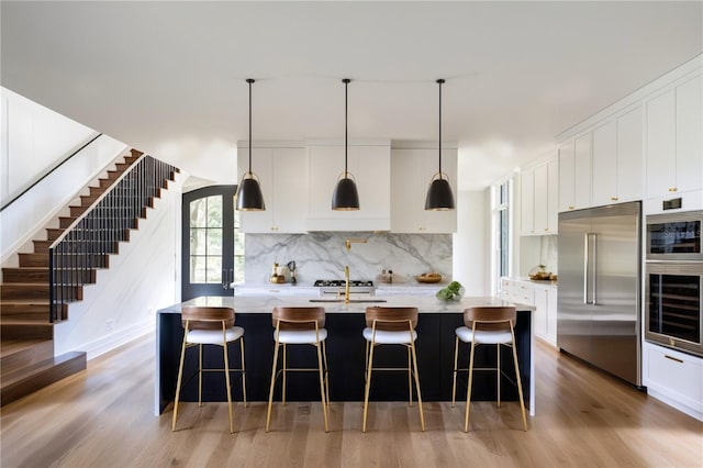 kitchen with white cabinetry, a center island with sink, and stainless steel built in refrigerator