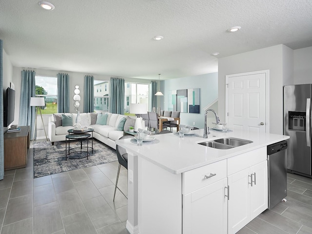 kitchen with sink, appliances with stainless steel finishes, a kitchen island with sink, a wealth of natural light, and white cabinets