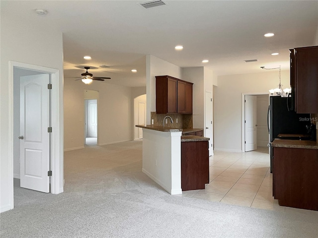 kitchen featuring hanging light fixtures, decorative backsplash, light carpet, ceiling fan with notable chandelier, and kitchen peninsula