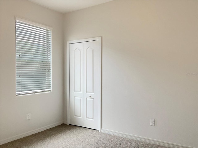 unfurnished bedroom featuring light colored carpet and a closet