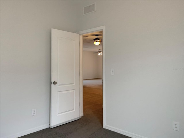 unfurnished room featuring dark colored carpet and ceiling fan